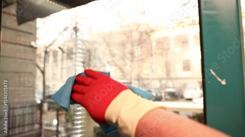 Wallpaper Mural A person in red glove cleans large glass window with blue cloth. Street view outside becomes clearer. Useful for hygiene, cleanliness, or property maintenance concepts. Torontodigital.ca
