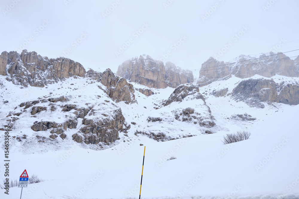 Obraz premium March 2025: view of Pordoi Pass and snowy road, Dolomites, Italy