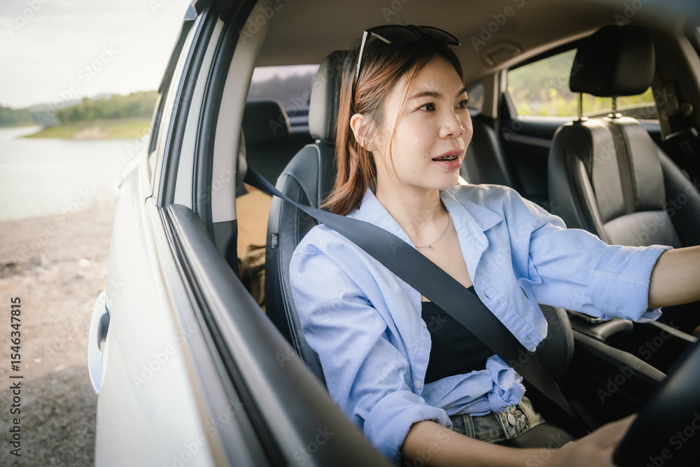A young Asian woman smiles confidently while driving a modern car, wearing sunglasses and a seatbelt, enjoying a safe, relaxed journey filled with freedom, comfort, and joy. A young Asian woman smiles confidently while driving a modern car, wearing sunglasses and a seatbelt, enjoying a safe, relaxed journey filled with freedom, comfort, and joy.