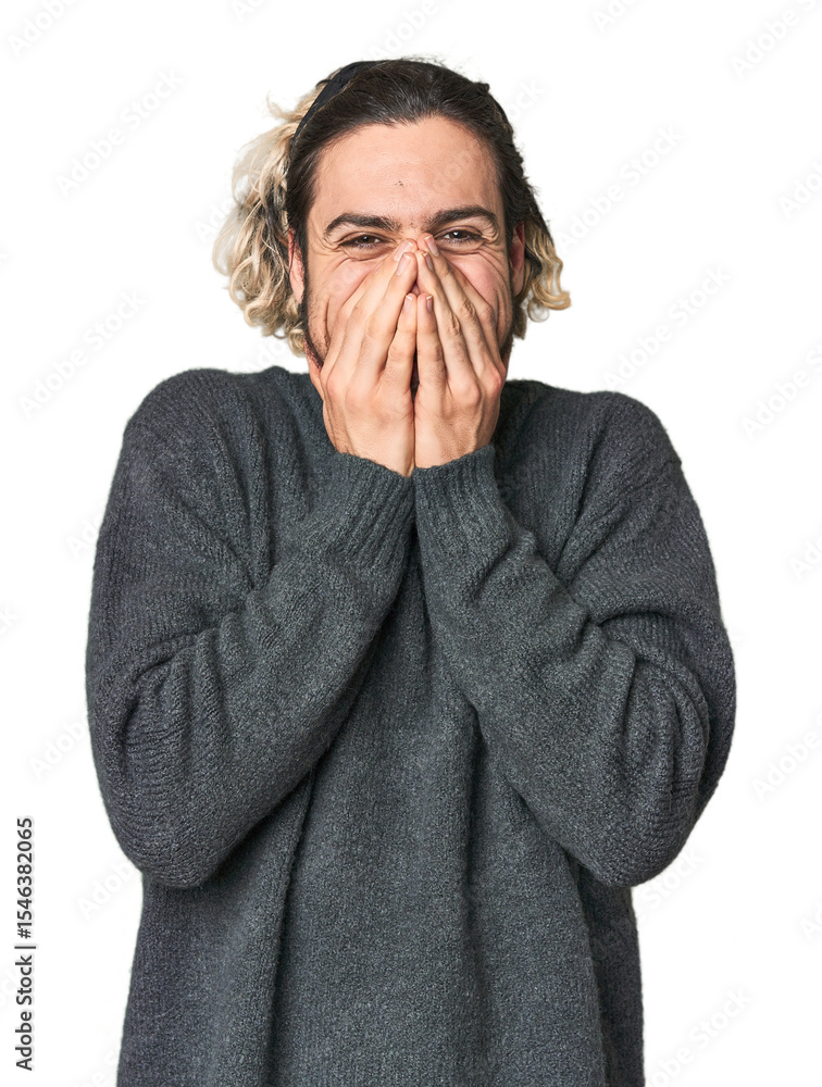 Young Caucasian man in studio setting laughing about something, covering mouth with hands. Young Caucasian man in studio setting laughing about something, covering mouth with hands.