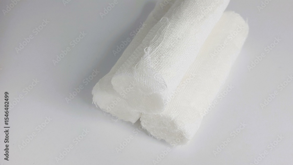 Fototapeta premium Close-up shot of three rolled gauze bandages on a white background. Ideal for medical, healthcare, or first aid concepts.