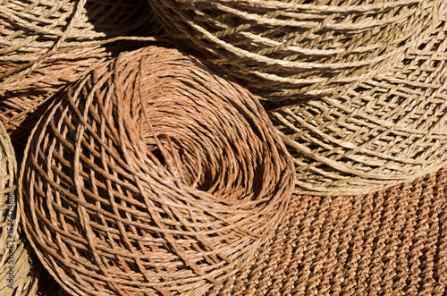 Natural raffia fibers are wound into spools against a crocheted background.