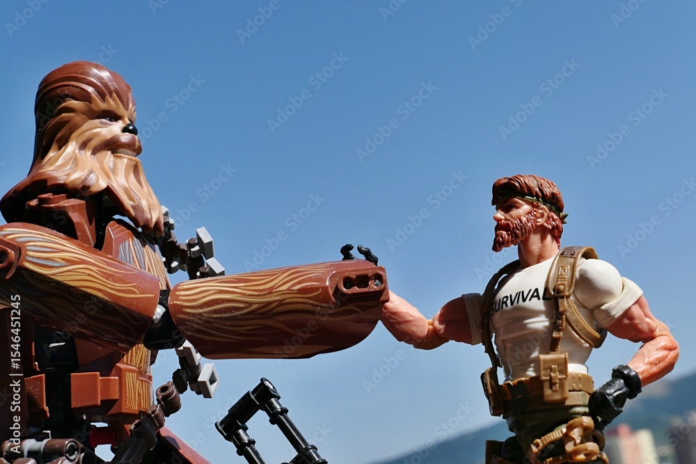 Naklejka premium LEGO Star Wars action figure of Wookie Chewbacca is going to shake hand (or paw) with GI JOE action figure of survival instructor Outback, Classified edition 2023. Blue skies background.