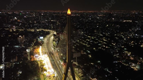 Aerial view of illuminated Rama VIII Bridge at night. Cable-stayed bridge crossing Chao Phraya River in Bangkok, Thailand, 4k
