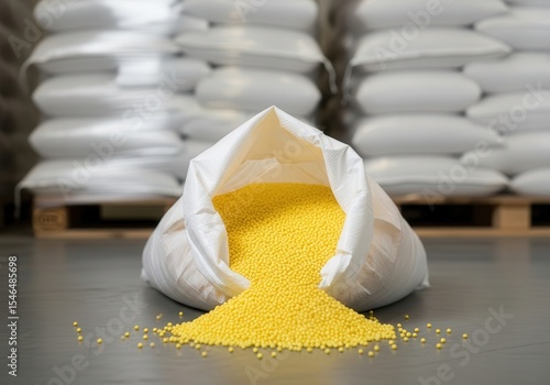 Yellow plastic pellets in an open bags on the background of a warehouse a pallets of raw material