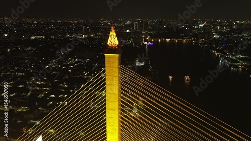 Aerial view of illuminated Rama VIII Bridge at night. Cable-stayed bridge crossing Chao Phraya River in Bangkok, Thailand, 4k