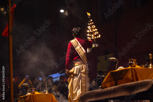 Ganga aarti, Portrait of an young unidentified male priest performing holy river ganga evening aarti at dashashwamedh ghat in traditional dress.