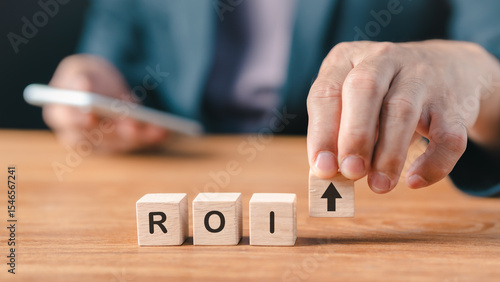 Return on investment (ROI) symbol with wooden blocks and arrow, hand of entrepreneur showing profit growth, financial strategy, business success, investment increase, corporate planning, finance goal