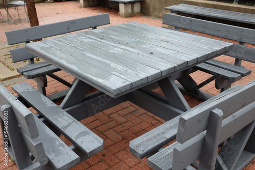 Foto large outdoor wooden table with benches on paved patio still wet from recent rai