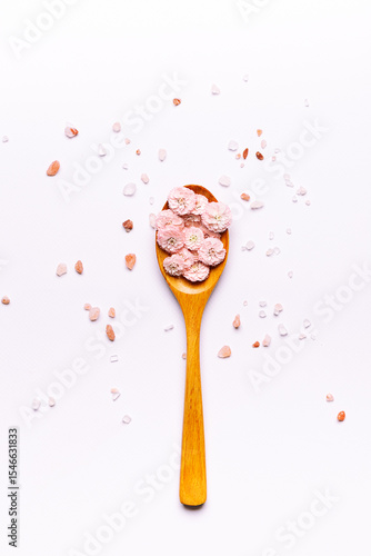 Canvas Print Artistic composition with wooden spoon fuli of beautiful arpmatic flowers on white background with cosmetic pink Himalaya salt