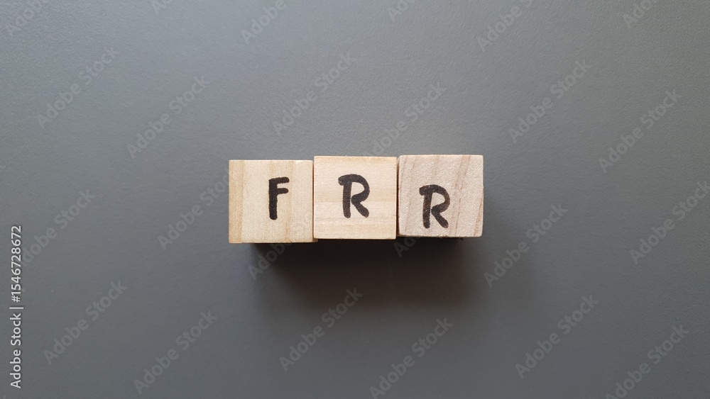 FRR acronym made of wooden letter cubes on dark background. Fonds de Réserve pour les Retraites (Pension Reserve Fund) FRR acronym made of wooden letter cubes on dark background. Fonds de Réserve pour les Retraites (Pension Reserve Fund)