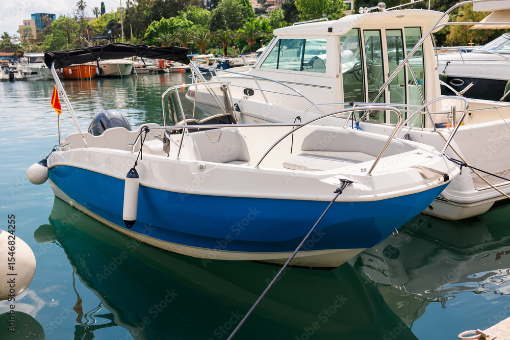 Fototapeta premium Small motorboats docked in calm marina water. Seaside lifestyle, coastal transportation, and nautical summer atmosphere