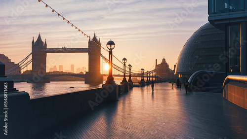Photography Sunrise casts warm hues over Tower Bridge as pedestrians stroll along Queen's Walk