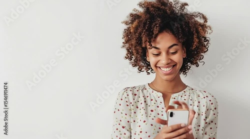 Connected & Contented: A radiant woman gazes with a heartwarming smile at her mobile phone. Capturing connection, digital contentment, and a moment of shared joy.