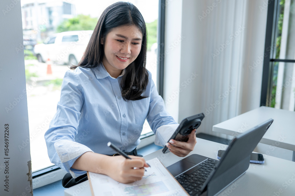 Fototapeta premium woman is sitting at a desk with a laptop and a cell phone