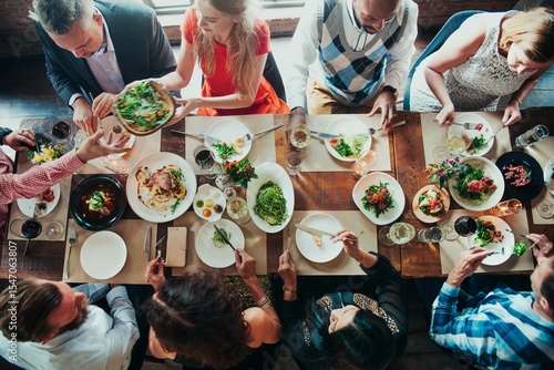Diverse group dining together, sharing food, enjoying a meal. Mixed ethnicities, men and women, social gathering, vibrant table setting, communal dining experience. Celebration and gathering.