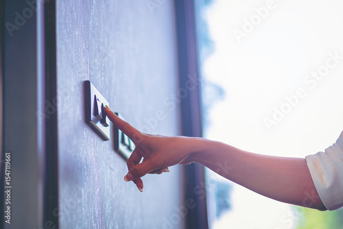 Woman turn off on light switch at the wall. Energy saving concept. Selected focus