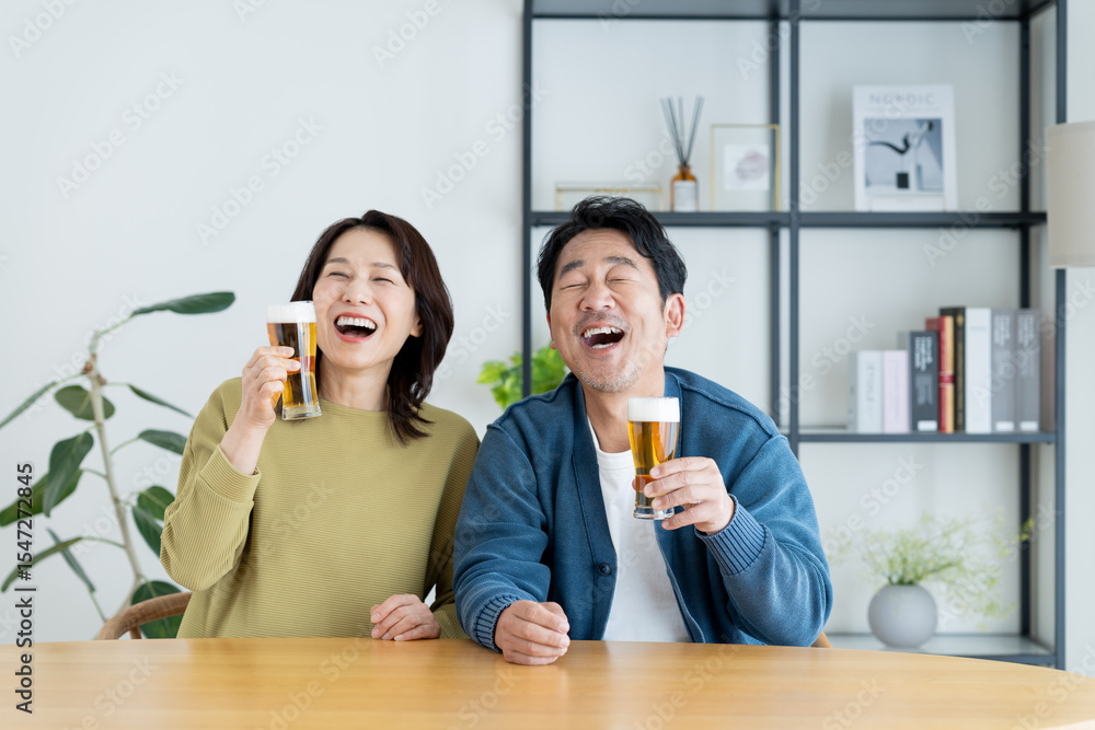 自宅でビールを飲む仲良しの夫婦 自宅でビールを飲む仲良しの夫婦