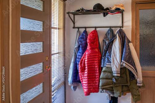 Tableau sur toile A cluttered entryway in a home, where winter coats, jackets, and hats are packed on a wall-mounted coat rack