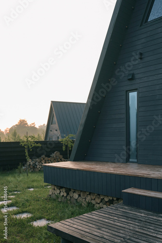 Wallpaper Mural Modern A-frame cabin exterior with woodpile under the terrace at sunrise, with clean lines and minimalist architecture in natural setting Torontodigital.ca