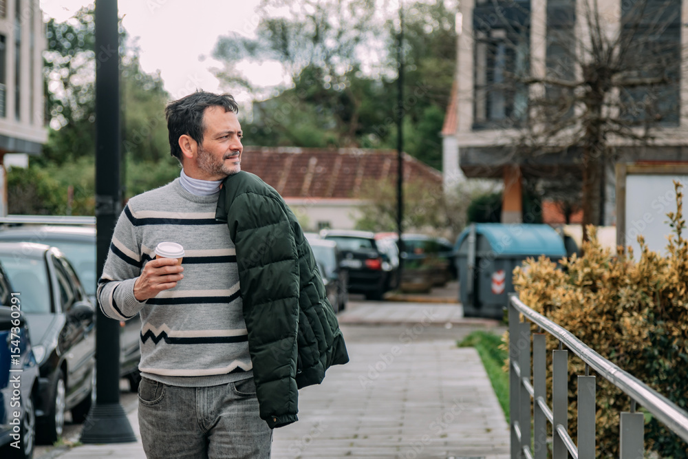 Fototapeta premium adult man drinking coffee while walking through the city