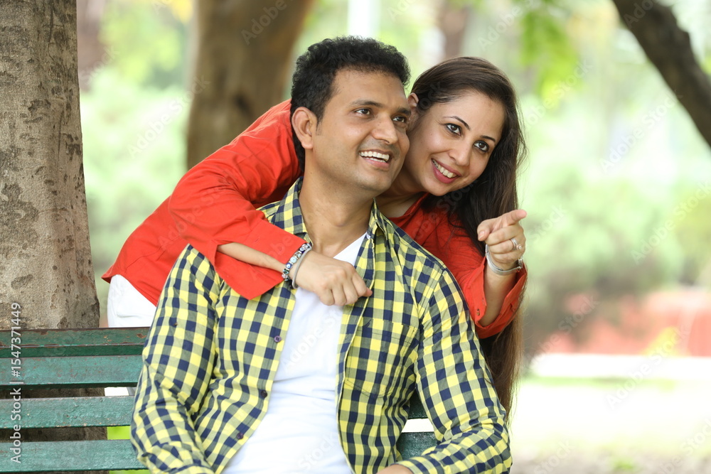 Naklejka premium Indian happy young couple pointing finger at park Romantic and Attractive happy couple in love, fun, hugging outside, relaxing, spending leisure time together, relationship and people concept.