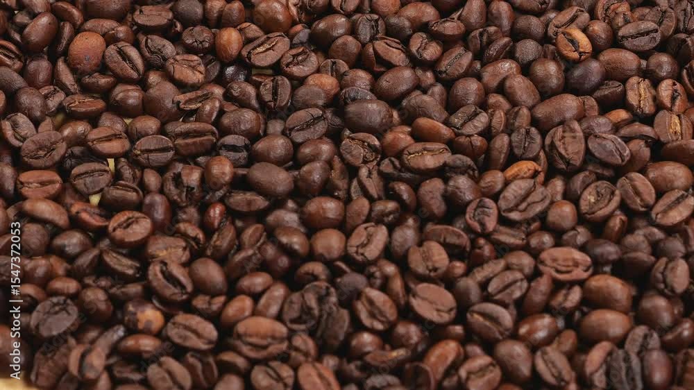 Close-up of many coffee beans slowly spinning, with coffee beans falling from above. A coffee background. Close-up of many coffee beans slowly spinning, with coffee beans falling from above. A coffee background.