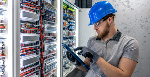 Visual panel inspection. Electrician near switchboard. Electrical system control.