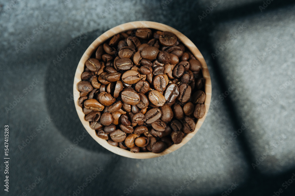 Fototapeta premium Coffee beans in wooden bowl with shadow on dark background