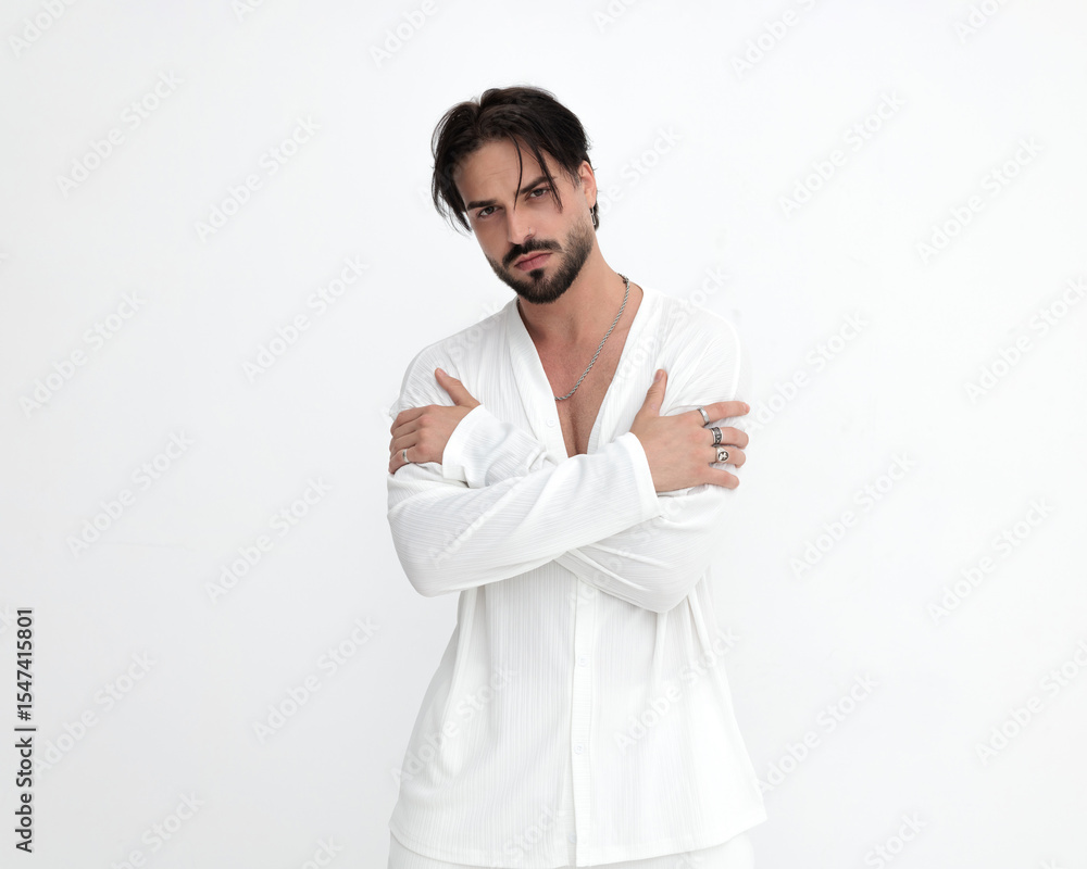 confident young man in white costume touching arms and posing confident young man in white costume touching arms and posing