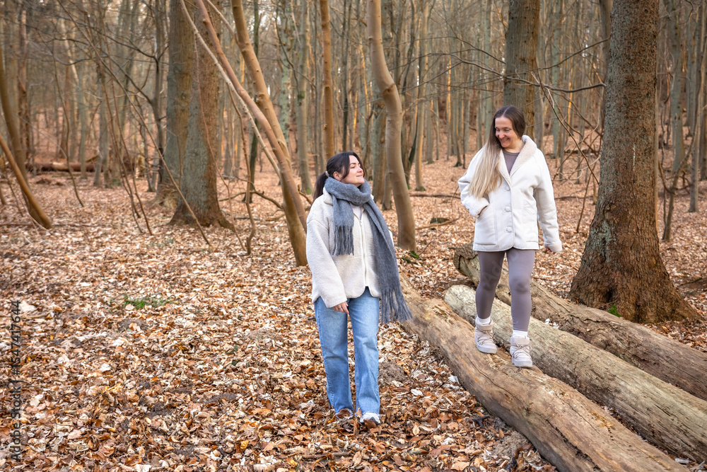 Fototapeta premium Two female friends on a walk in the forest. Friends walking through the forest. People in nature.