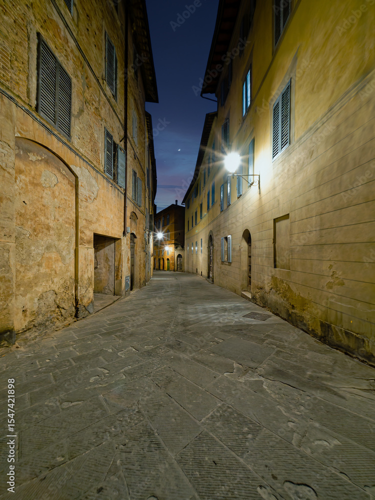 Obraz premium Twilight casts a soft glow over the narrow alleys of Siena, where historic buildings and elegant facades create an emotive and timeless urban scene. Travel to Tuscany, Italy.