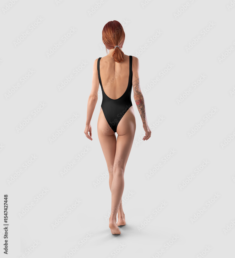 Template of a black one-piece swimsuit with a bare back, on a slender redheaded girl with a tattoo, isolated on a background. Template of a black one-piece swimsuit with a bare back, on a slender redheaded girl with a tattoo, isolated on a background.