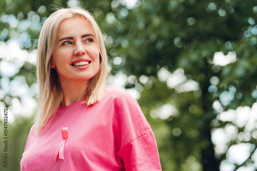 Smiling woman wearing pink ribbon supporting breast cancer awareness in park Smiling woman wearing pink ribbon supporting breast cancer awareness in park