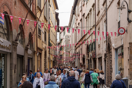 Fototapeta Naklejka Na Ścianę i Meble -  Busy narrow street in Lucca, Italy, with old buildings and walking tourists.