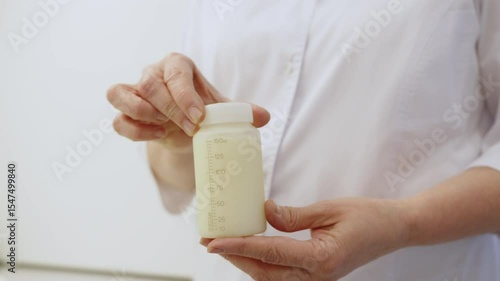 An individual holds a bottle of donor breast milk, showcasing the resource in a medical setting.