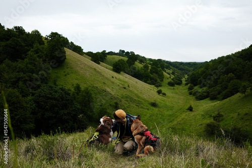 Wall Mural Female traveler hugs his two dogs against backdrop of the Zagajicka brda hills in Serbia