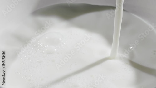 Milk is streaming and splashing leaving beautiful round ripples on the milk surface. Slow motion close up video
