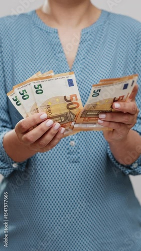 Unrecognizable woman counting fifty-dollar bills close-up. Vertical video.