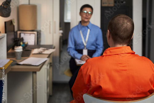 Papier peint Caucasian young adult woman in orange prison uniform sitting with back to camera