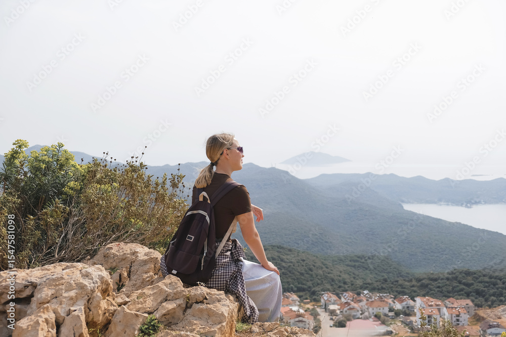 Naklejka premium Young woman enjoying peaceful solo travel scenic mountain and sea views. Mindful moment of digital detox, eco-tourism, and personal reflection in nature. Concept of freedom and intentional living.
