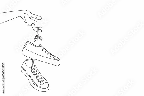 Single continuous line drawing a pair of sneakers with laces hanging from the fingers. Easy to carry. Attracts attention. National Two Different Colored Shoes Day. One line design vector illustration