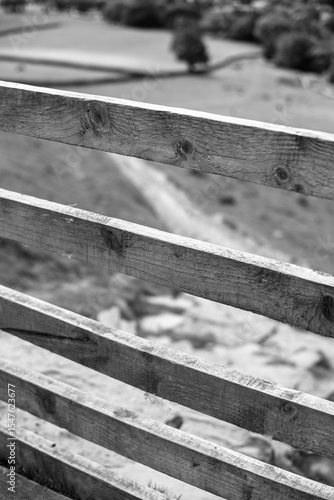 Wallpaper Mural A black and white close-up of wooden fence rails diagonally crossing the frame. The background is blurred revealing a path leading to a distant landscape in the Peak District Torontodigital.ca