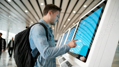 Man uses touchscreen kiosk at modern airport terminal