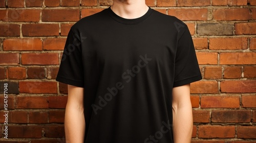 Studio shot showcasing a person wearing a plain black t-shirt against a brick wall