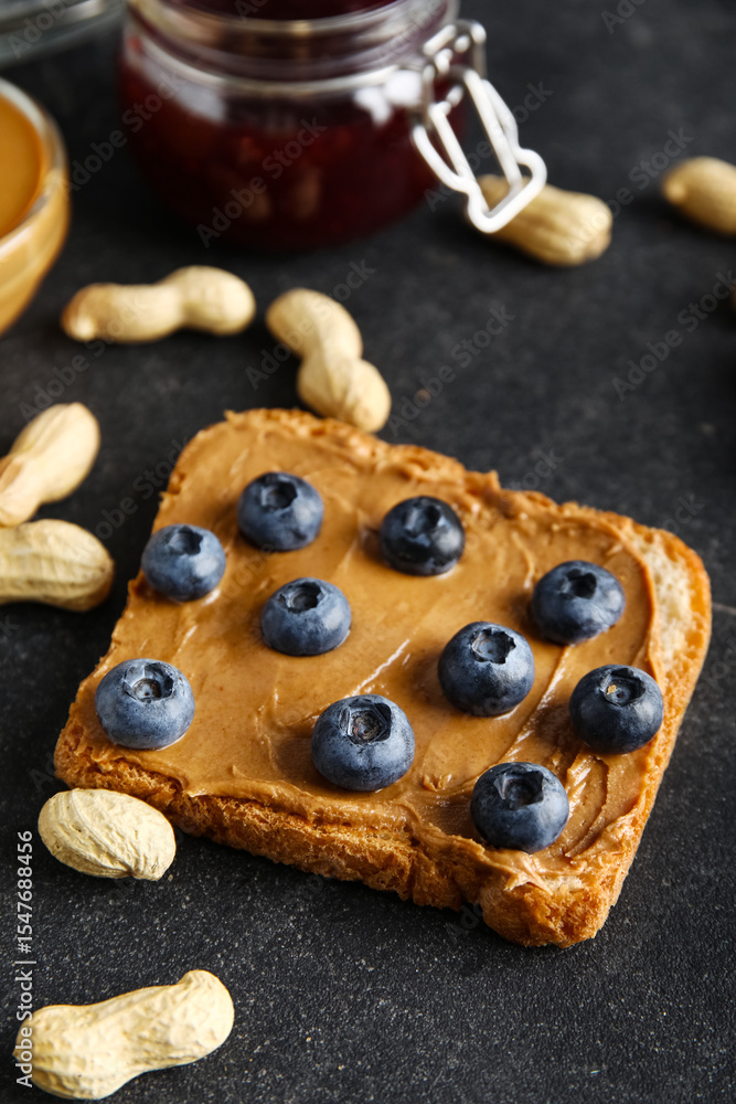 Fototapeta premium Toast with peanut butter and blueberries on black background