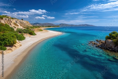 Coastal view of an idyllic beach featuring blue waters cliffs and distant mountains under a partly cloudy sky
