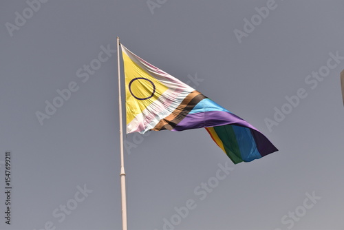 Intersex‑inclusive Progress Pride flag flying against a clear blue sky—symbolizing unity, visibility, and intersectional LGBTQIA+ pride