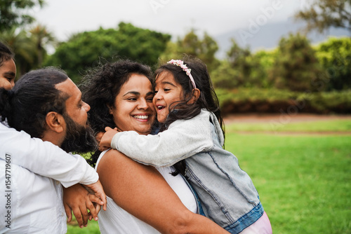 Happy indian family having fun playing with children outdoor at city park - Summer time, love and parenthood concept - Main focus on mother face