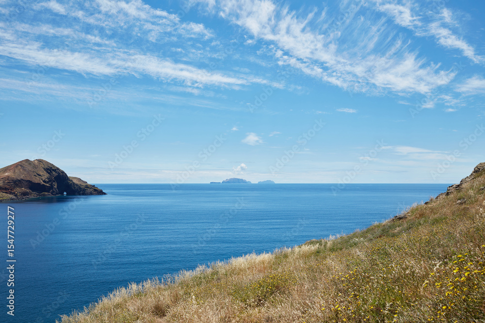 Coastal landscape view with distant islands and blue ocean under a sunny sky Coastal landscape view with distant islands and blue ocean under a sunny sky